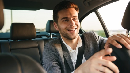 Lächelnde Person am Rücksitz eines Autos