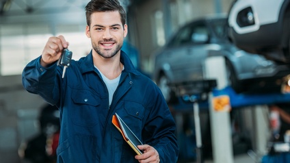 Automechaniker hält einen Autoschlüssel entgegen