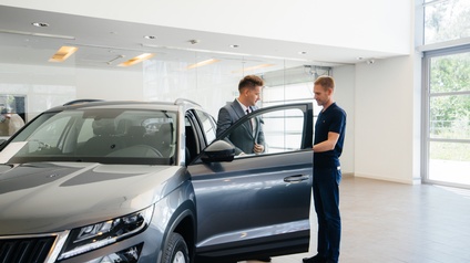 Zwei Personen bei Auto mit geöffneter Fahrertüre stehend