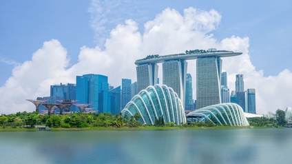 Stadtansicht von Singapur: Skyline in der Marina Bay mit modernen Hochhäusern und fantasievollen Bäumen unter blauem Himmel
