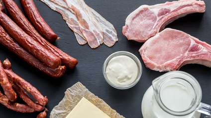 Topshot verschiedener Fleisch- und Milchprodukte auf dunklem Untergrund