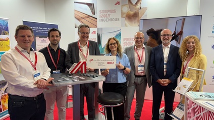 Sieben Personen stehen am AUSTRIA-Messestand lächelnd nebeneinander.