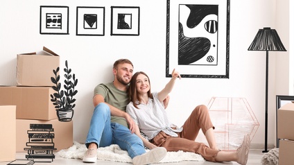 Zwei Personen sitzen auf einer Decke am Boden eines Wohnraumes, daneben stehen Umzugskartons und Elemente für die Einrichtung des Raumes werden gezeichnet visualisiert