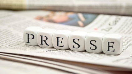 Nebeneinander gereihte Würfel mit dem Schriftzug Presse auf Zeitung liegend