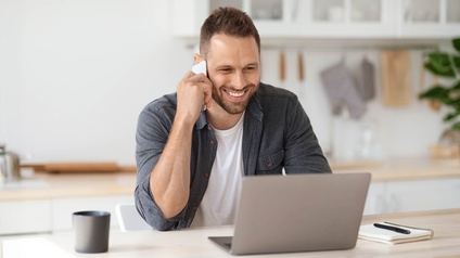 Ein Mann am Laptop und mit Telefon