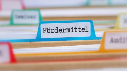 Aktenmappe mit bunten Trennblättern, auf dem blauen steht Fördermittel