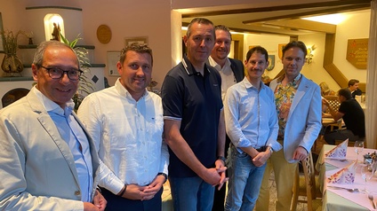 Sechs Männer stehen lächelnd nebeneinander in einem Gasthaus beim Mobility Talk