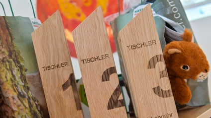 Drei Siegestrophäen aus hellem Holz mit den großen Nummern für die Plätze 1, 2 und 3 und dem Wort Tischler in dunkelbrauner Schrift