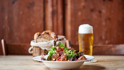 Ein Salat und ein Glas Bier stehen auf einem Tisch.
