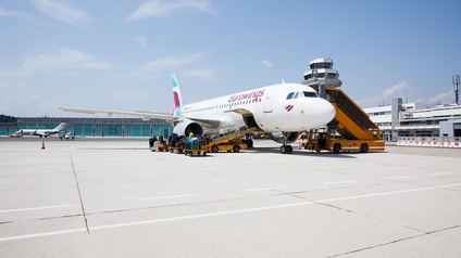 Flugzeug auf der Rollpiste vor dem Abfertigungsgebäude am Flughafen Klagenfurt