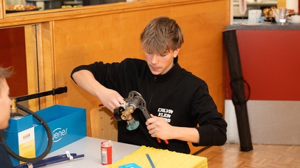 Schüler sitzt an einem Tisch und bearbeitet Installationsrohre mit einer Rohrzange