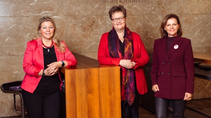 Telesklav und Legner lehnen am Tisch, Rab steht rechts daneben. Alle haben ein rotes Oberteil