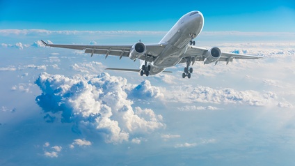 Flugzeug im Aufwärtsflug über Wolken unter blauem Himmel
