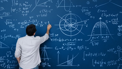 Ein Mann schreibt auf eine blaue Wand mathematische Formeln