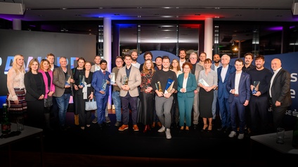 Eine große Personengruppe posiert für ein Bild, einige Personenhalten Auszeichnungen und Awards in Händen.