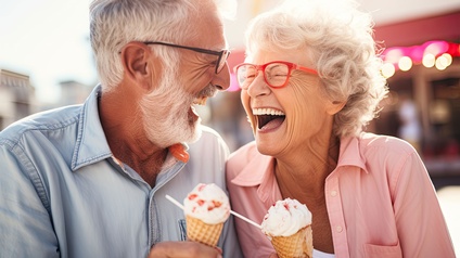 Ein älteres Paar (Mann und Frau) lachen und schlecken ein Eis.