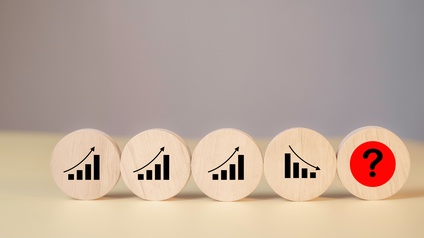 Fünf Holzkreise stehen nebeneinander auf einem Holztisch. Auf den ersten drei Kreisen sind jeweils Statistikbalken mit einem Pfeil nach oben. Auf dem vierten sind Statistikbalken und ein Pfeil nach unten. Auf dem fünften ist ein Fragezeichen