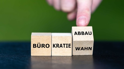 Hand dreht Würfel und ändert den Ausdruck Bürokratiewahn in Bürokratieabbau