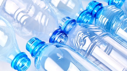 Nahaufnahme von blauen Plastikflaschen, die auf hellem Hintergrund nebeneinander liegen.