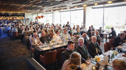 viele Menschen sitzen in einem Raum an Tischen