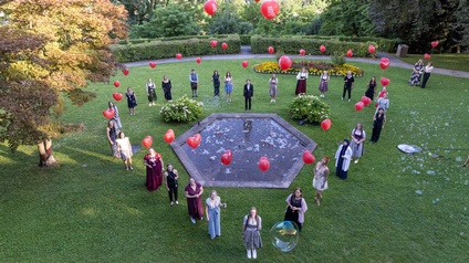 Die Teilnehmer:innen beim Bundeslehrlingswettbewerb der Floristik haben sich in Herzform aufgestellt und halten einen roten Luftballon mit der Aufschrift Herzensangelegenheiten in der Hand.