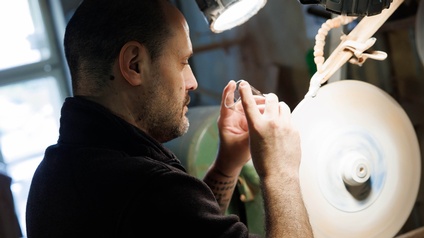 Ein Mann schleift Glas am Schleifstein