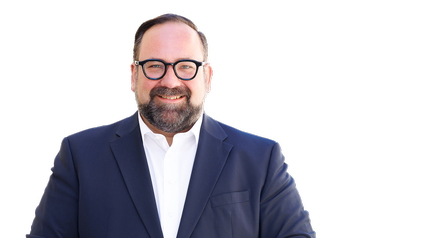 Porträt einer Person mit kurzen Haaren, Brille, Bart, weißem Hemd und dunkelblauem Sakko