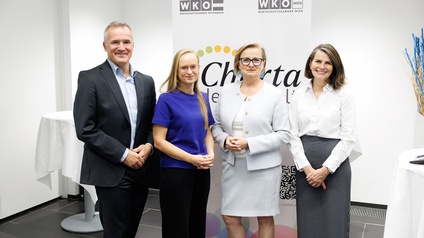 Porträt von vier Personen, die nebeneinander vor einem Aufsteller mit den Logos der WKÖ und der Wirtschaftskammer Wien stehen