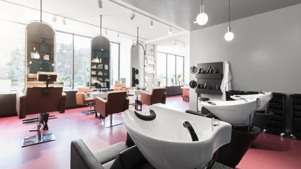 Ein menschenleerer Friseursalon mit rotem Boden, hohen Fenstern und Spiegeln