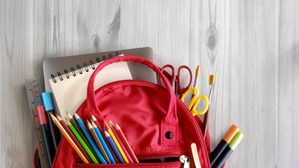 Schulrucksack und Schulmaterial auf weißer Holztisch Hintergrund. Zurück zum Schulkonzept
