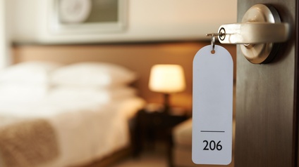 Blick durch die Tür eines Tiroler Hotelzimmers auf ein frisch gemachtes Bett. 