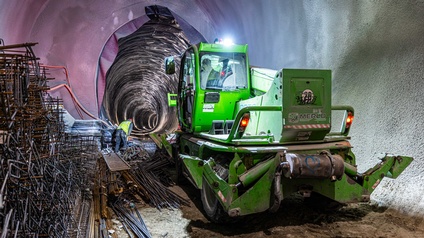 In einem Tunnel steht ein grünes Baufahrzeug. Links daneben sind Metallstäbe