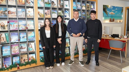 Sunayda Tek, Didem Kirmizi, Bora Eker und Efe Eker stehen in ihrem Büro in Telfs vor einer Wand, an der Reisekataloge aufgereiht sind.