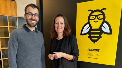 Ein Mann und eine Frau stehen vor dem Plakat der Energiebiene
