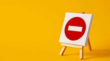 Roter Kreis mit in der Mitte gerade verlaufendem weißen Strich auf weißer Leinwand auf Staffelei stehend vor gelbem Hintergrund