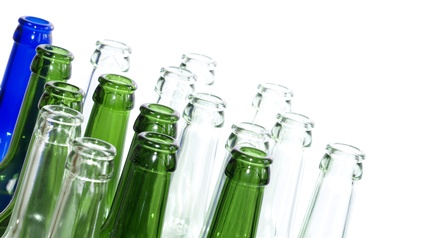 Detailsansicht leerer Glasflaschen in unterschiedlichen Farben auf weißem Hintergrund