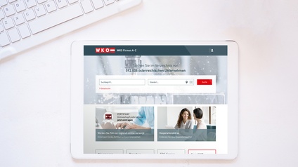 Tablet mit geöffnetem WKO Firmen A-Z auf einem weißen Untergrund, daneben ragt eine Tastatur in das Bild