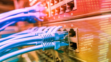 Nahaufnahme vieler, gräulicher Kabel, die an eine Internetbox angeschlossen sind