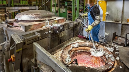 Person in Schutzkleidung verarbeitet Aluminium in einer Werkstatt