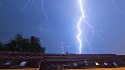 Ein Blitz schlägt hinter einem haus ein.