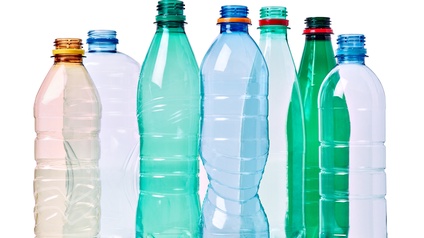 Vor weißem Hintergrund stehen verschieden farbige und große Flaschen aus Plastik ohne Deckel