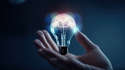 Eine Hand hält eine Glühbirne mit einem leuchtenden Gehirn darinnen