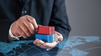 Eine Person hält in den Händen drei kleine Container. Darüber ist eine Grafik der Kontinente der Welt gelegt. Von manchen Städten führen Linien zu anderen Städten