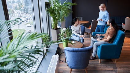 Personen sitzen in einem floralen und bequemen Besprechungsraum