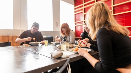 Vier Kollegen sitzen beim Mittagessen in der Firma