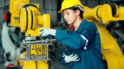  Mechatronikerin inspiziert einen Robotergreifarm