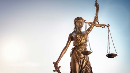 Statue der Justitia mit Waage der Gerechtigkeit vor blauem Himmel