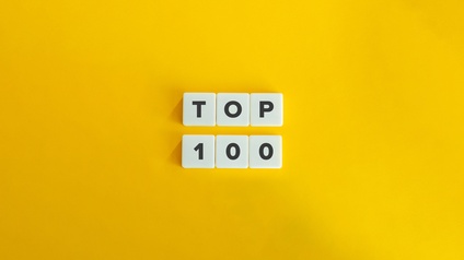 Illustration eines gelben Hintergrund. In der Mitte liegen in zwei Reihen jeweils drei weiße Würfel. In der oberen Reihe ist auf jedem Würfel ein Buchstabe, wodurch sich das Wort Top ergibt. In der unteren Reihe sind Zahlen, wodurch sich 100 ergibt