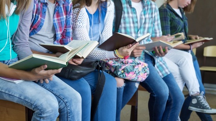 Schulkinder sitzen in einer Reihe und lesen Bücher