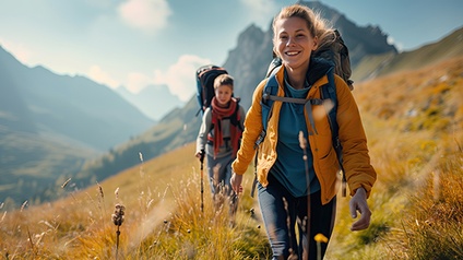 Frau mit Kind beim Wandern im Herbst vor einer Bergkulisse.